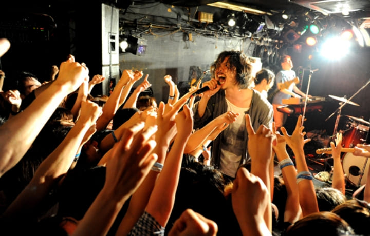 ライブハウスでオーディエンスを煽るバンドのボーカル